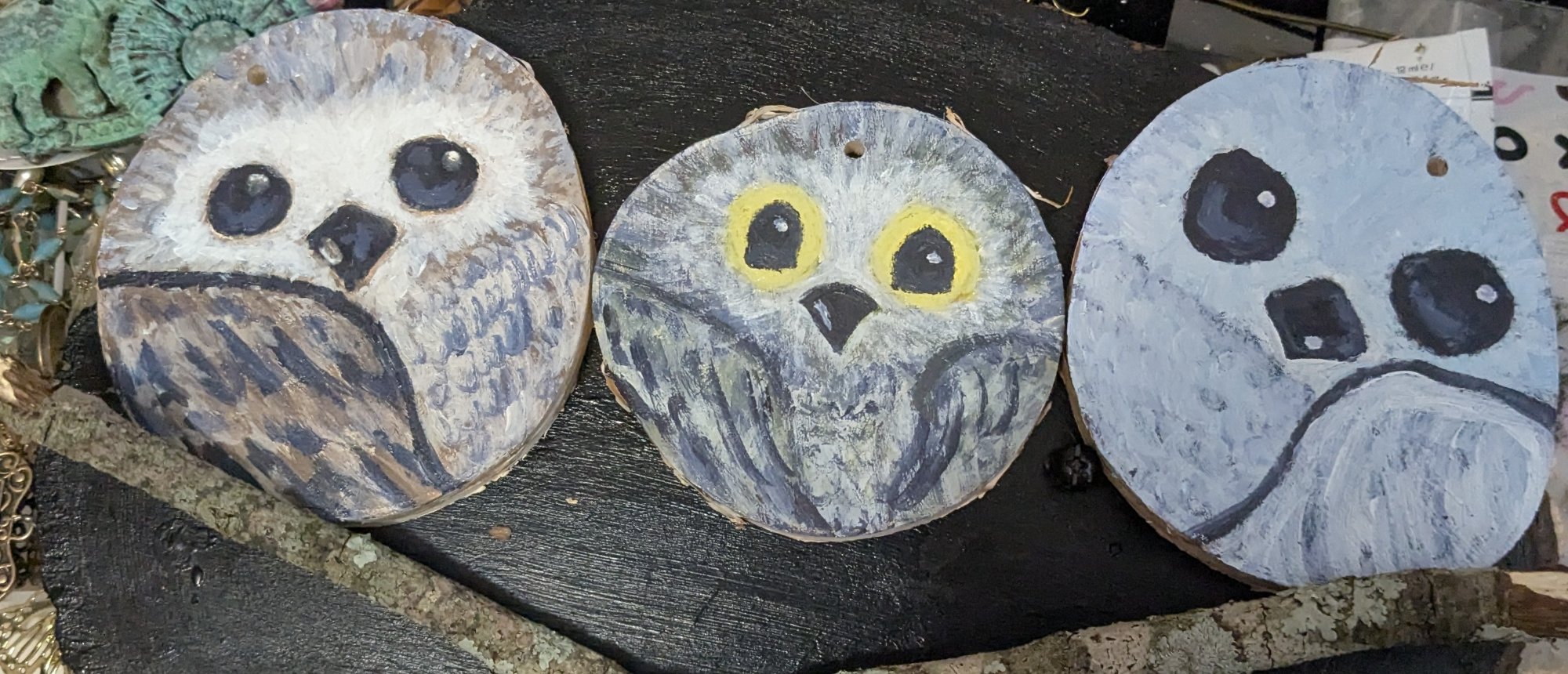 Three owl faces painted on wood slice rounds