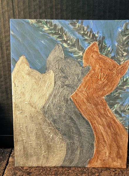 Two cats in gold and copper against a blue sky and olive foliage