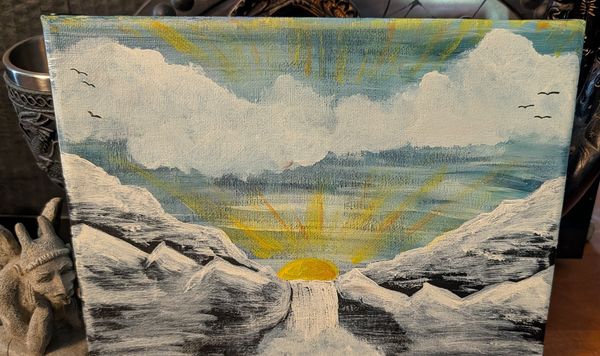 Sun rising between grey mountains over a pale waterway