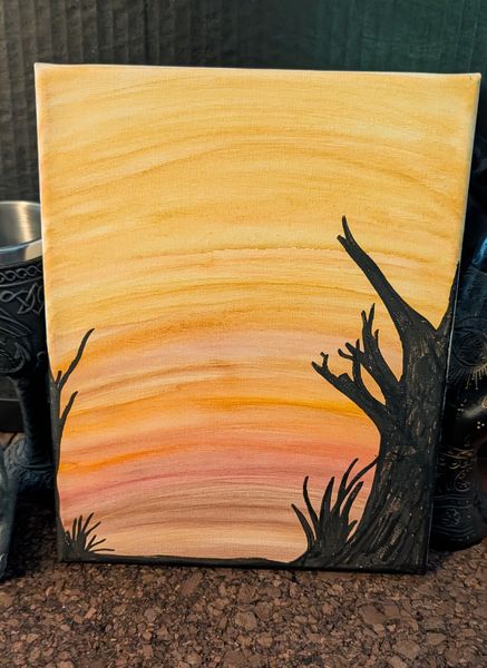 Bare black branches silhouetted against an orange and peach sunset