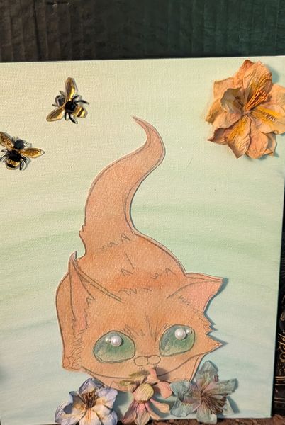 A peach cat with large green eyes among bees and pressed flowers