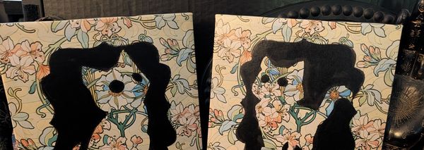 Two cats framed in black cut-outs over a blue and cream floral pattern