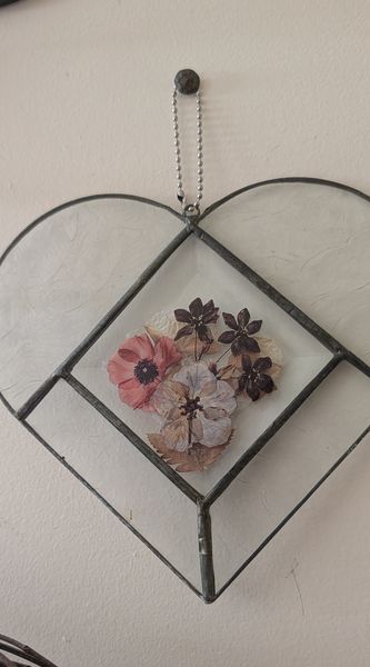 Pressed pink and mauve blooms set in a diamond within a leaded glass heart